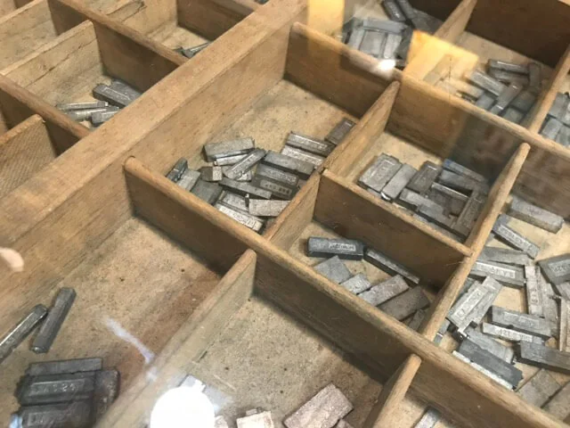 Close view of lead type lying face-up in the compartments of a wooden case.